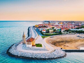 A coastal town with a prominent church, a beach, and a rocky breakwater. - Apartment in Caorle Near Sea Beach & Pool (Caorle)