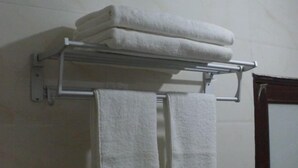 A bathroom with a towel rack holding two folded towels and a single towel hanging. - Youxi Sanming Red Lantern Hotel (Youxi)