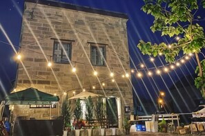 A stone building with string lights, a green tent, and potted plants. - Cafe Bar & Inn - Stone and Iron (Otaru)