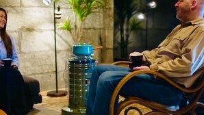 Two people seated in a room with a stone wall, a large potted plant, and a floor lamp. - Cafe Bar & Inn - Stone and Iron (Otaru)