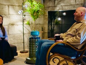 Two people seated in a room with a stone wall, a large potted plant, and a floor lamp. - Cafe Bar & Inn - Stone and Iron (Otaru)
