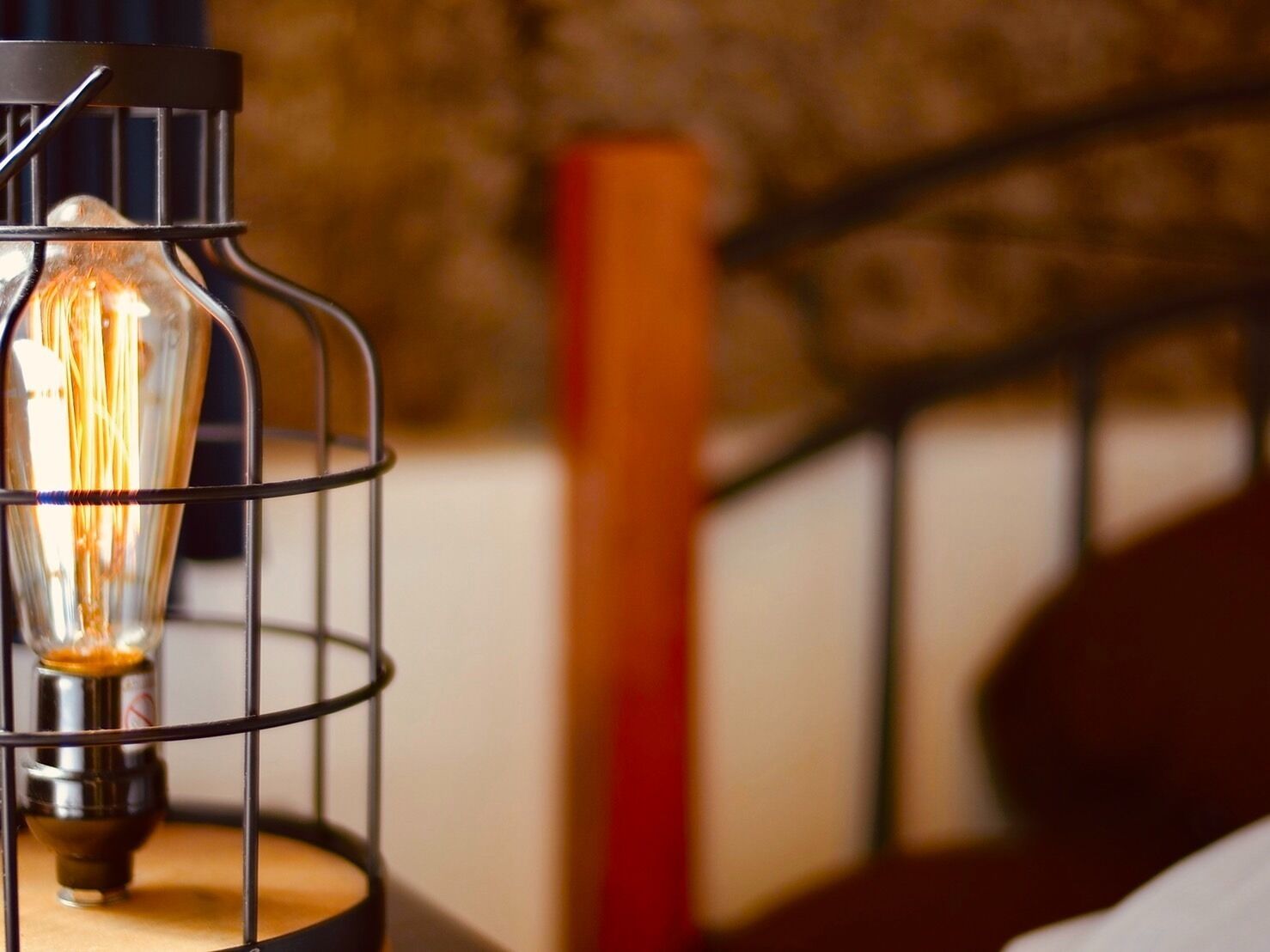 A close-up of a metal-framed light fixture with an exposed bulb, placed on a wooden surface.