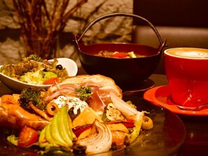 Un repas composé de poulet rôti, de légumes et d’une tasse de café noir, le tout servi sur une table.