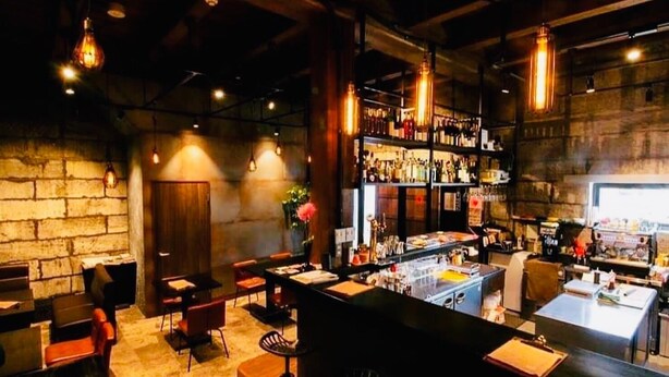 A bar area with wooden walls, hanging lights, and a bar counter. - Cafe Bar & Inn - Stone and Iron (Otaru)