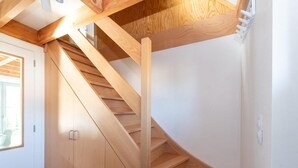 A modern interior with a wooden staircase leading to a loft area. - Holiday Home in Koksijde Near Beach (Koksijde)
