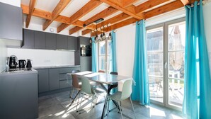 A modern kitchen with grey cabinets, a stainless steel sink, and a dining area with a table and chairs. - Holiday Home in Koksijde Near Beach (Koksijde)