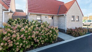 A residential building with a red-tiled roof, brick exterior, and a garden with hydrangea bushes. - Holiday Home in Koksijde Near Beach (Koksijde)