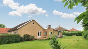 Een gelijkvloers huis van baksteen met een schuin dak, een schotelantenne en een verzorgd gazon.