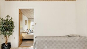 Een slaapkamer met een bed, een kamerplant en een houten vloer.