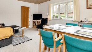 Een moderne woonkamer met een eethoek, houten plafond en grote ramen.