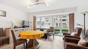 Una sala de estar moderna con una mesa de comedor, sofás y una televisión.