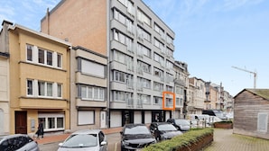 Un edificio residencial de varios pisos, con fachada de ladrillo y sección superior gris.