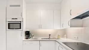 A modern kitchen with white cabinets, a built-in oven, a coffee maker, and a dishwasher. - Flat With Terrace & Play Area (Blankenberge)
