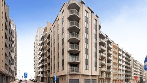 A multi-story residential building with balconies, a parking sign, and a pedestrian crossing. - Flat With Terrace & Play Area (Blankenberge)