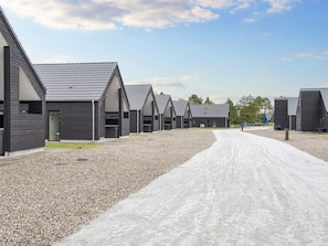 A row of modern, dark-colored cabins with pitched roofs, arranged along a gravel path. - 5 Star Holiday Home in Romo (Rømø)