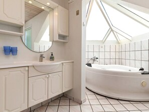 Ein modernes Badezimmer mit freistehender Badewanne, einem großen Spiegel und einem Oberlicht.
