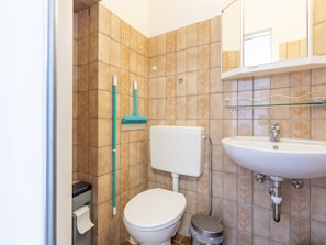 A bathroom with a toilet, sink, and a mop leaning against the wall. - Nice Apartment With Shared Pool (Middelkerke)
