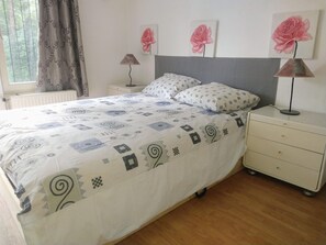 Cozy retreat with a neatly made bed, bedside table, and large window.