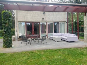 Relax in the covered patio area, featuring a round table, four chairs, a sofa, and a coffee table.