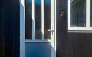 A door with a white frame and a glass panel, a small window with a white frame, and a doorbell. - 6 Person Holiday Home in Skjern (Skjern)