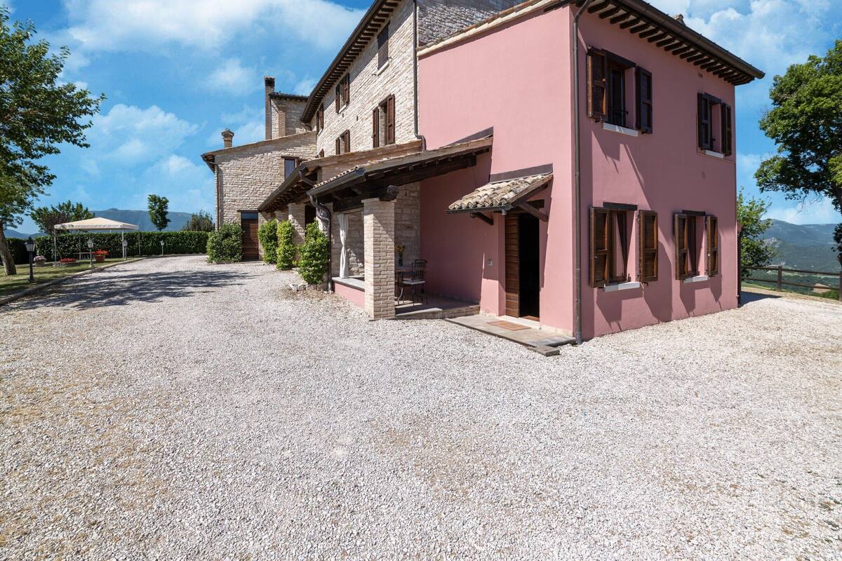 A two-story house with a gravel driveway and a covered patio area.
