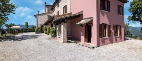 A two-story house with a gravel driveway and a covered patio area.