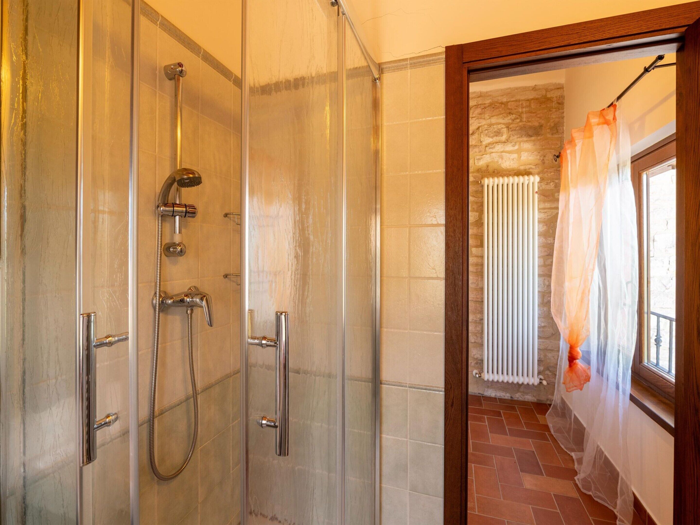 Eine begehbare Dusche mit Glaswänden, Chromarmaturen und einer Steinwand im Hintergrund.