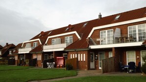A row of terraced houses with a front garden, a wooden fence, and a small outdoor seating area. - Sky Blue Comfortable Holiday Residence (Friedrichskoog)