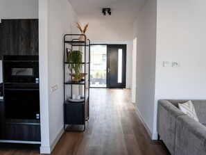A modern living room with a grey sofa, a black entertainment unit, and a wooden floor.