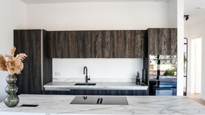 Una cocina moderna con armarios de madera oscura, encimera de mármol y lavamanos empotrado.