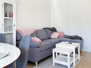 A modern living room with a grey sofa, a white coffee table, and a cabinet with glass doors. - 4 Star Holiday Home in Ljustero (Ljusterö)