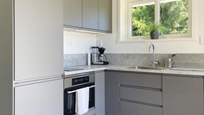 A modern kitchen with a built-in oven, a coffee maker, and a window with a view of greenery. - 4 Star Holiday Home in Ljustero (Ljusterö)
