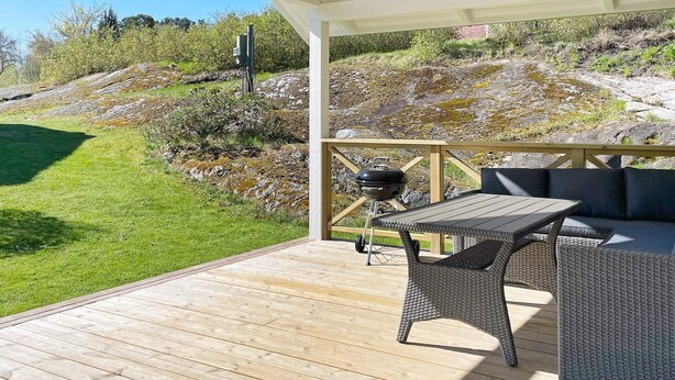 An outdoor patio with a table and chairs, a barbecue grill, and a view of a grassy hillside. - 4 Star Holiday Home in Ljustero (Ljusterö)