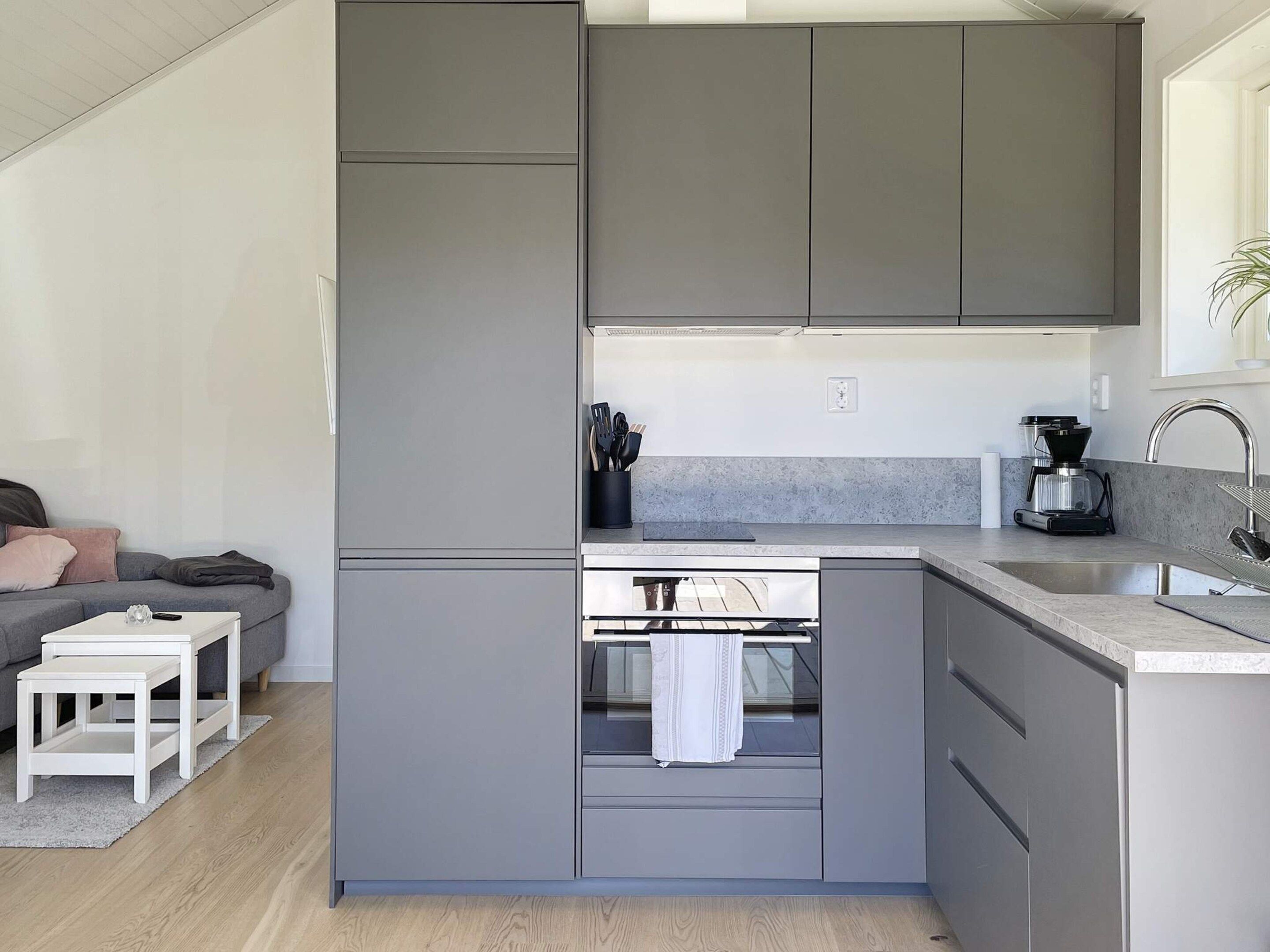 A compact kitchen with grey cabinets, a built-in oven, and a coffee maker.