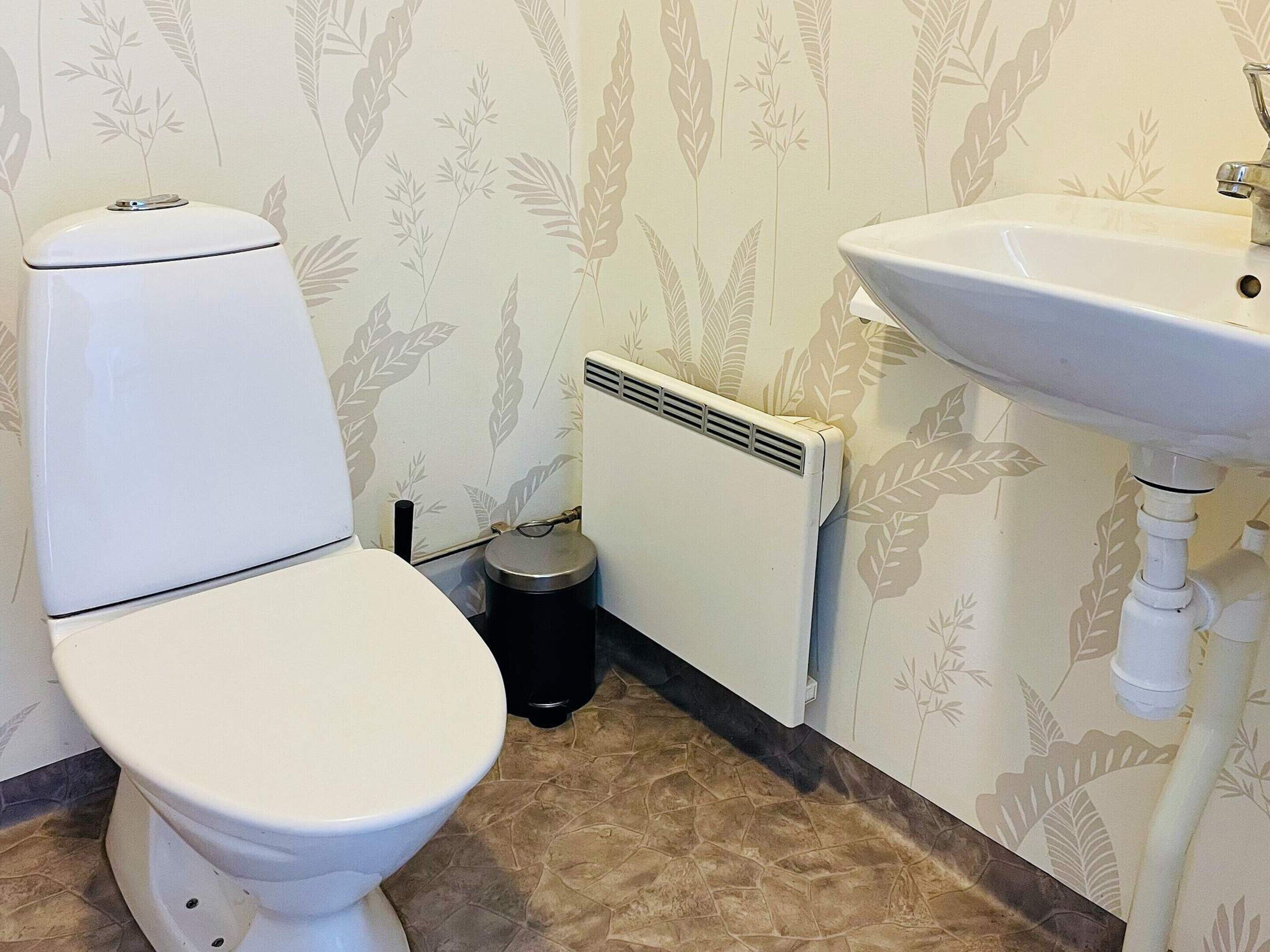 A bathroom with a toilet, a radiator, and a sink.