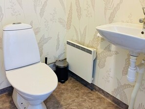 A bathroom with a toilet, a radiator, and a sink. - 4 Person Holiday Home in Nosund (Nosund)