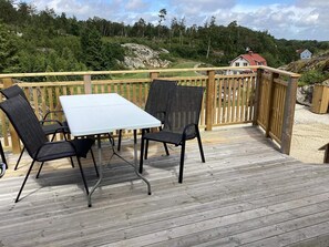 A wooden deck with a table and chairs, overlooking a forested hillside. - 4 Person Holiday Home in Nosund (Nosund)