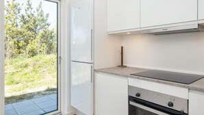 A modern kitchen with a built-in oven, a stovetop, and a refrigerator. - 5 Star Holiday Home in Romo (Rømø)