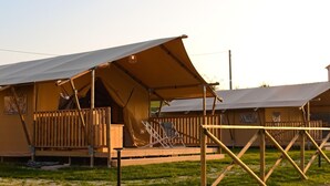A row of safari tents with wooden railings and a covered walkway. - Farmhouse Tent in Marche Near Adriatic Sea (Fermo)