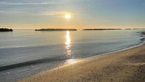 A beach with calm waters reflecting the sun, distant islands, and a clear sky. - Farmhouse Tent in Marche Near Adriatic Sea (Fermo)