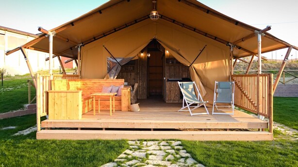 A tent with a wooden deck, seating area, and a small table. - Farmhouse Tent in Marche Near Adriatic Sea (Fermo)
