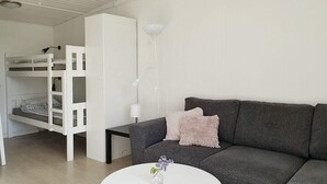 A modern living room with a grey sofa, a white round coffee table, and a bunk bed with a white wardrobe. - 4 Star Holiday Home in Karlskrona (Karlskrona)