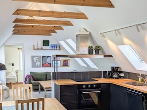 A modern kitchen with a sloped ceiling, built-in oven, and wooden beams. - 5 Person Holiday Home in Albaek (Aalbaek)