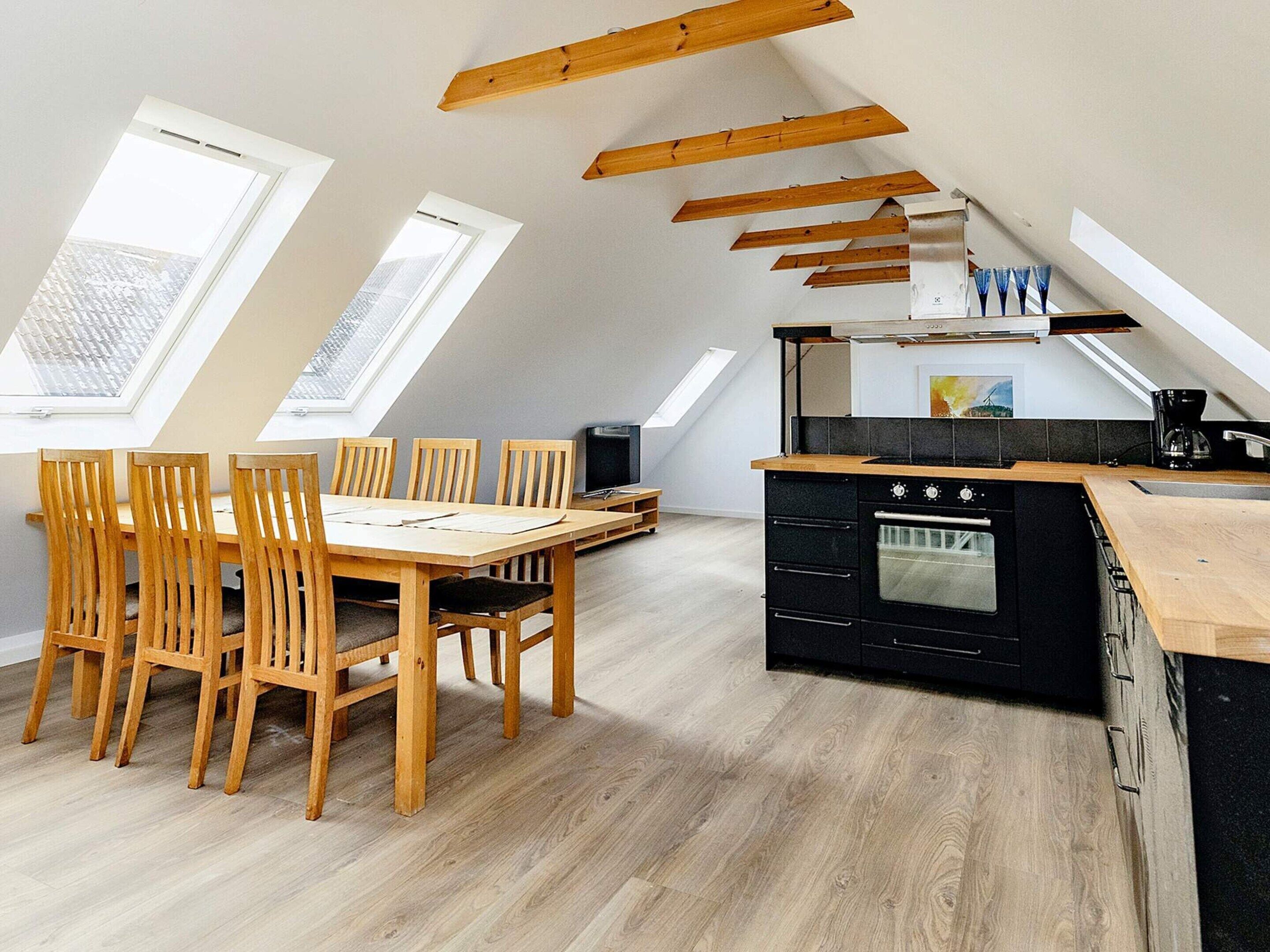 Un loft moderno con comedor, cocina y tragaluces.