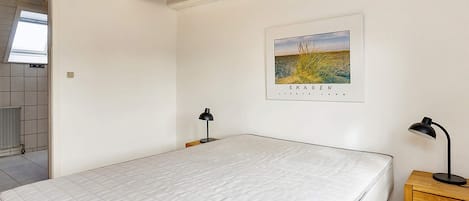 A bedroom with a large bed, two bedside tables with lamps, a wooden ceiling, and a framed picture on the wall.