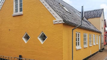 A yellow building with a sloped roof and multiple windows.