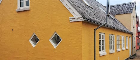 A yellow building with a sloped roof and multiple windows.