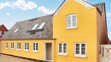 A yellow building with a gabled roof and multiple windows.