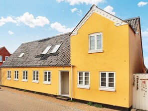 A yellow building with a gabled roof and multiple windows.