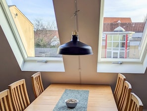 A dining area with a table, chairs, a hanging light fixture, and skylights. - 5 Person Holiday Home in Albaek (Aalbaek)